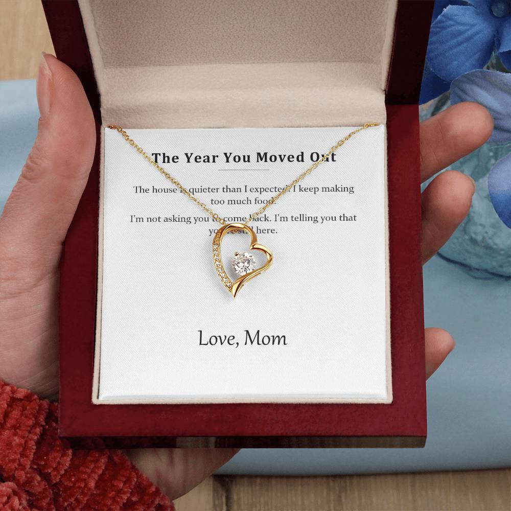 Hand holding the luxury gift box with the gold heart necklace, on a red knitted background