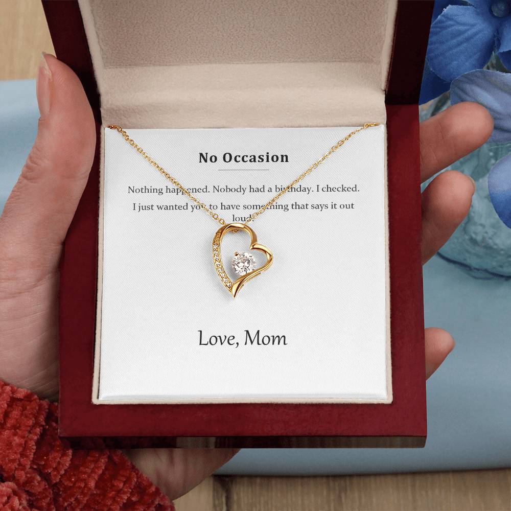 Hand holding the luxury gift box with the gold heart necklace, on a red knitted background