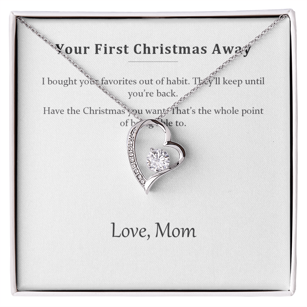 Silver heart pendant necklace on a printed message card reading Your First Christmas Away, in a white gift box