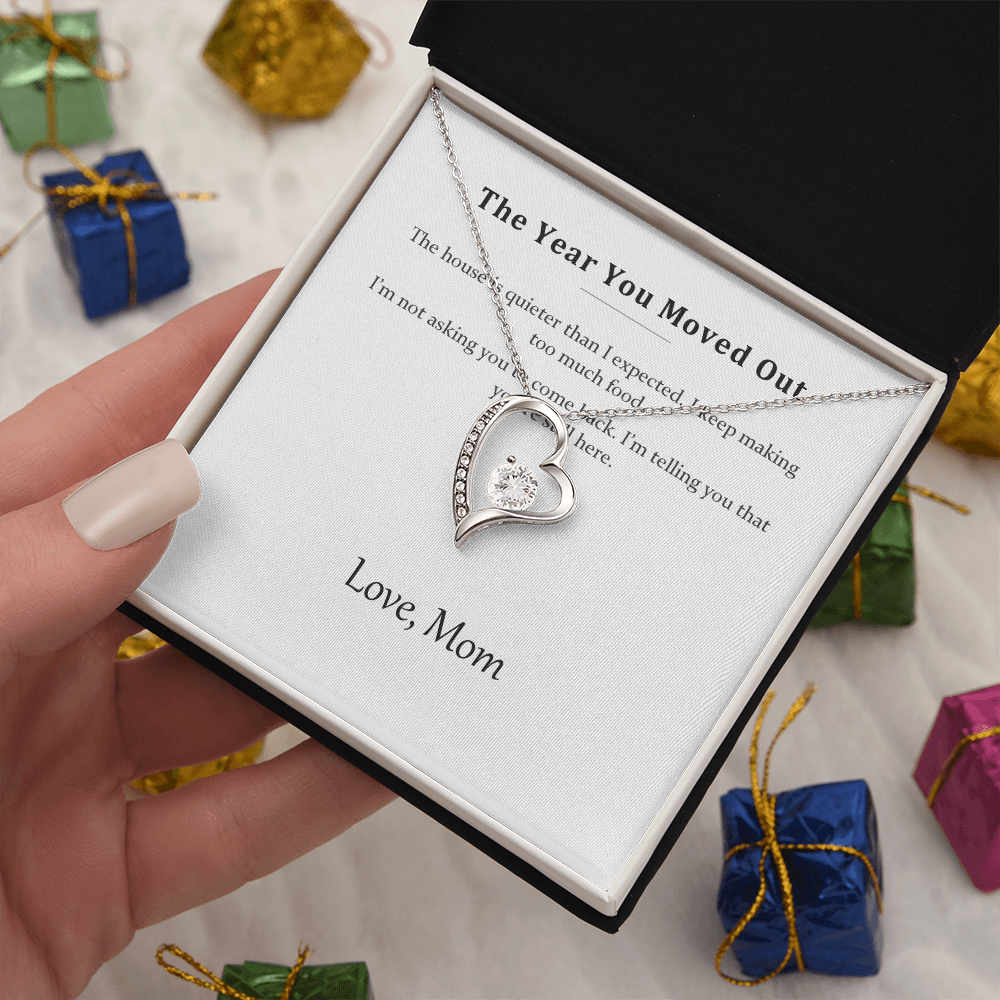 Silver heart necklace and message card held above wrapped presents and ribbon