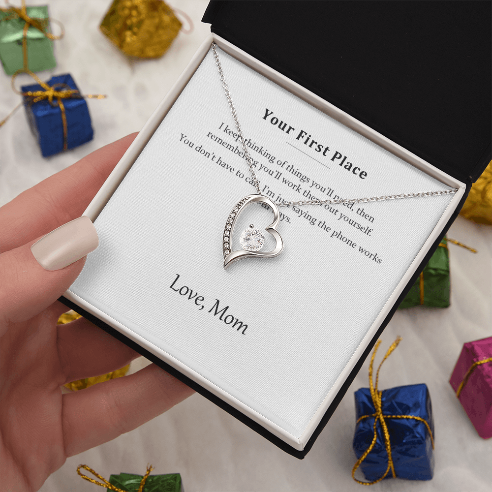 Silver heart necklace and message card held above wrapped presents and ribbon