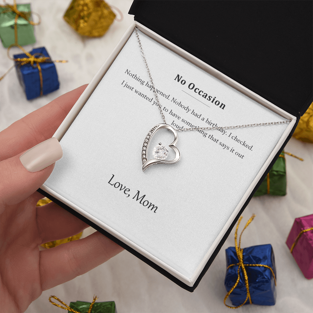 Silver heart necklace and message card held above wrapped presents and ribbon