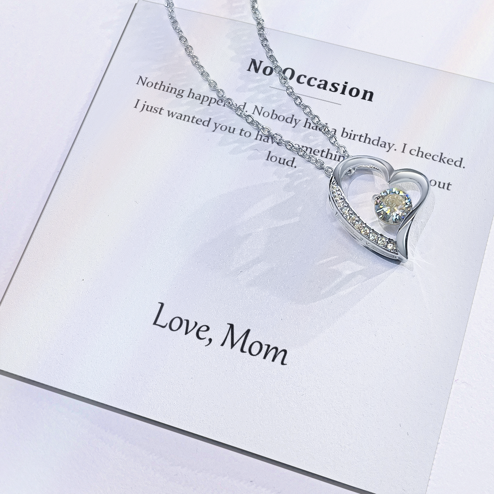 Close view of the printed message card with the silver heart pendant resting on it