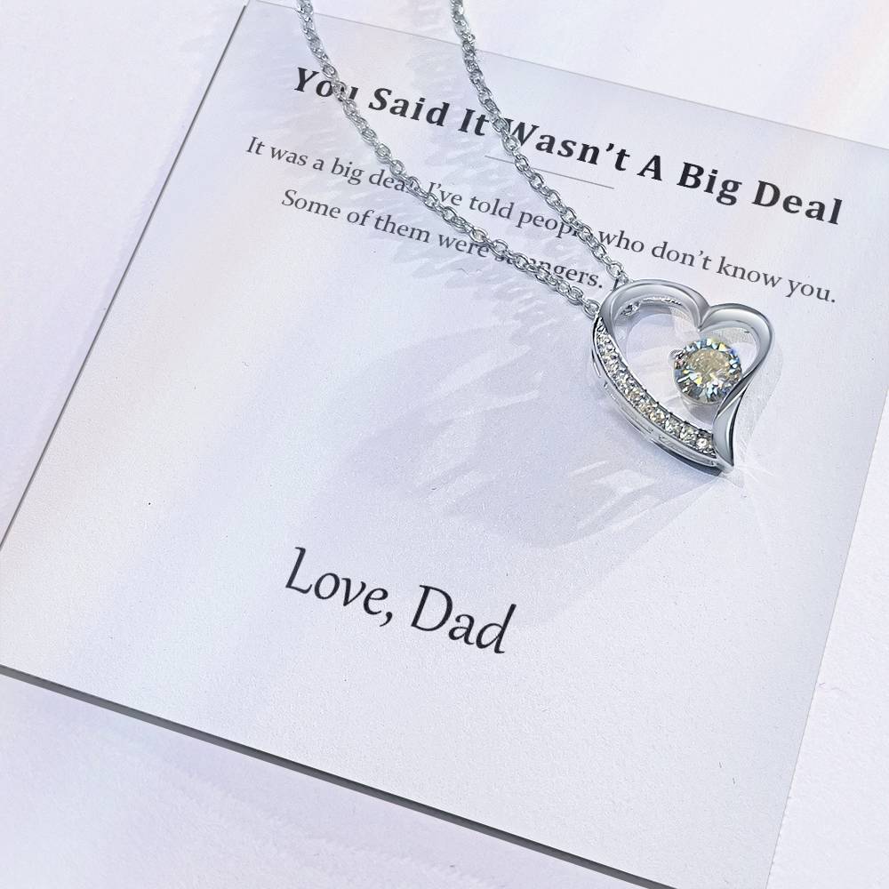 Close view of the printed message card with the silver heart pendant resting on it