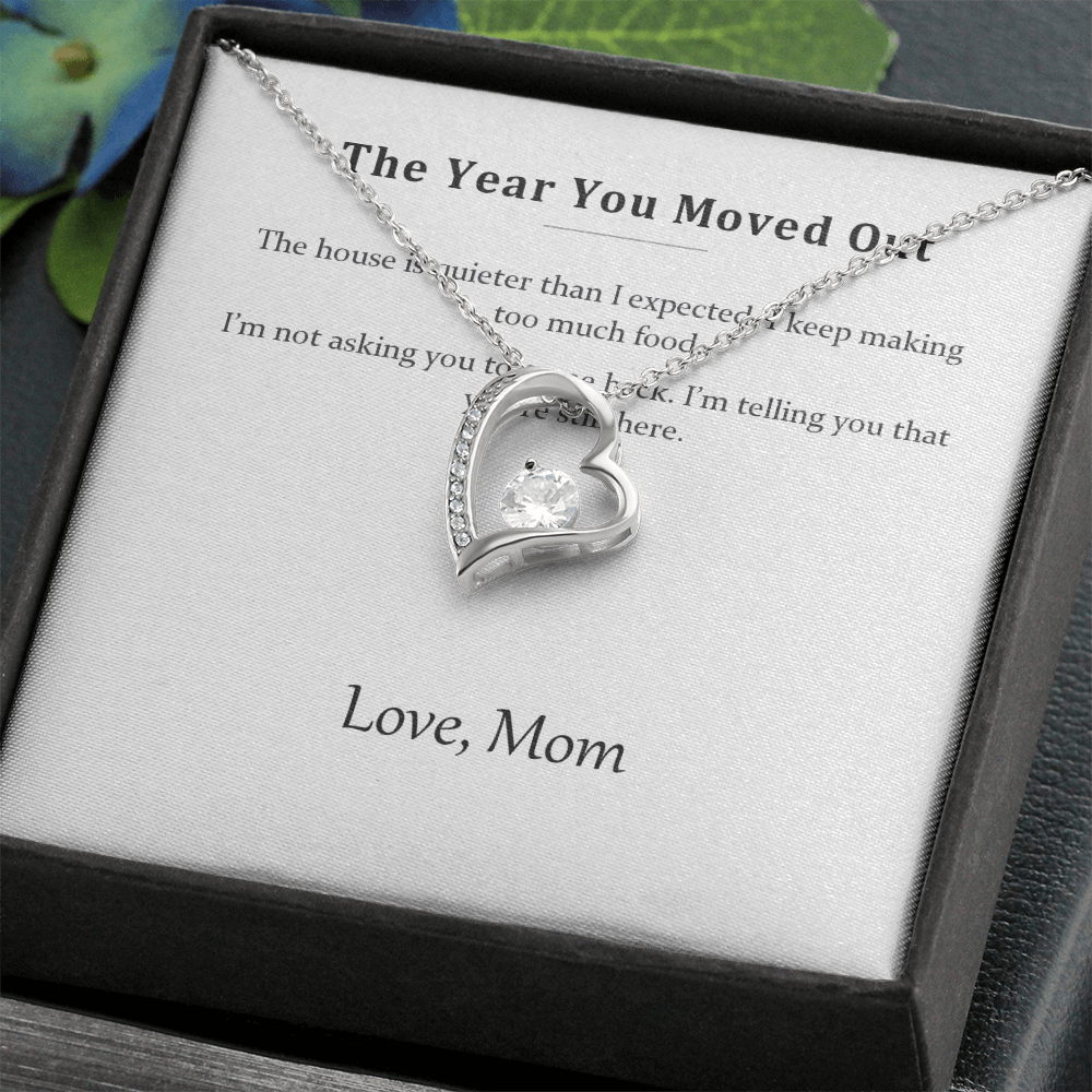 Silver heart necklace on the message card in a black gift box, styled with foliage