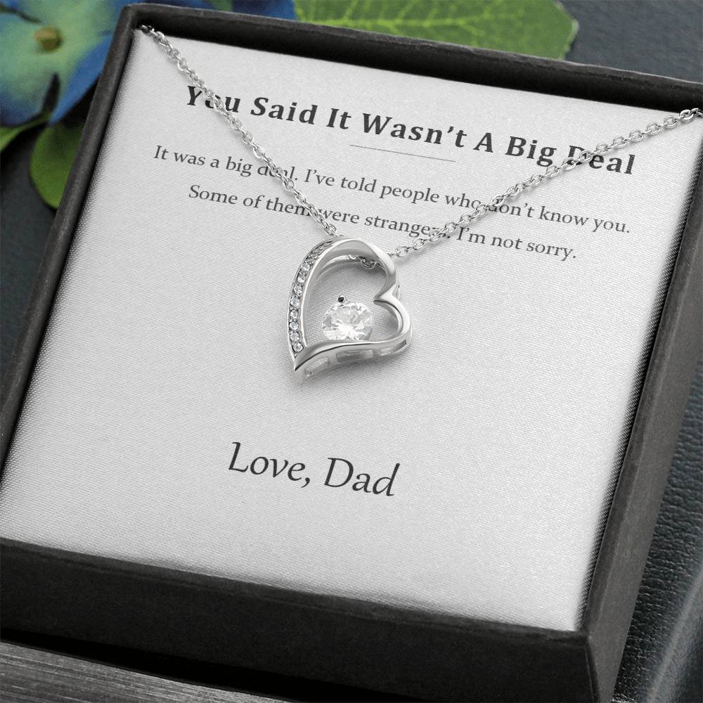 Silver heart necklace on the message card in a black gift box, styled with foliage