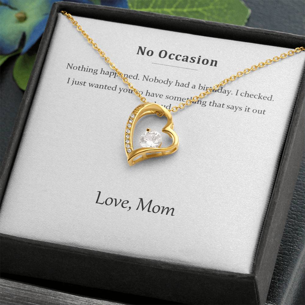 Gold heart pendant resting on the printed message card inside a black gift box